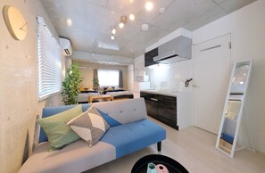 A modern, compact living space with a sofa, kitchenette, and a dining area. - Landmark Namba C (Osaka)