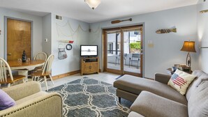 Ein Wohnzimmer mit einem Holzesstisch, Stühlen, einer Couch und einem Fernseher.