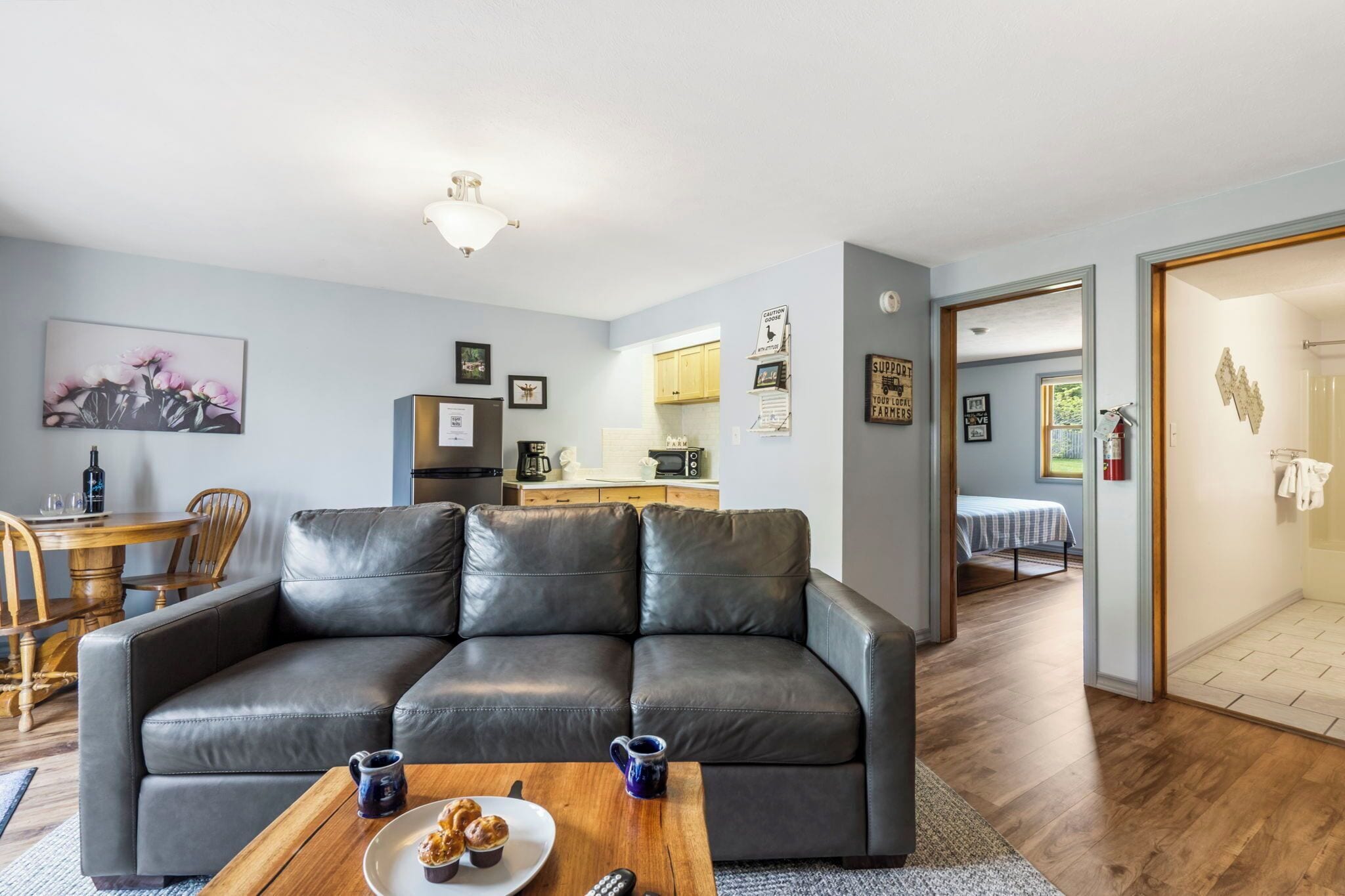 A modern living room with a leather sofa, wooden coffee table, and a dining area with a wooden table and chairs.