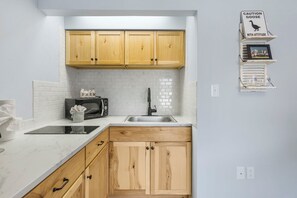 A kitchen with wooden cabinets, a microwave, a sink, and a caution sign about a goose.