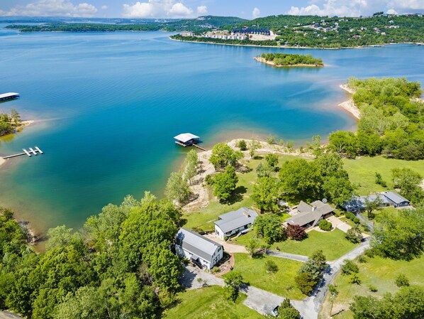 Vista aérea de una propiedad junto al lago con varias casas, un muelle y un bote.
