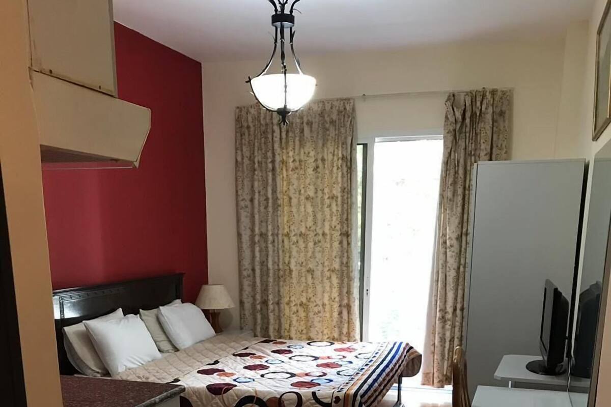 A hotel room with a bed, a desk, a chair, a television, and a window with curtains.