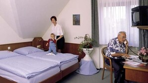 A hotel room with two beds, a desk, a television, and a potted plant. - Hotel Ockenheim (Ockenheim)