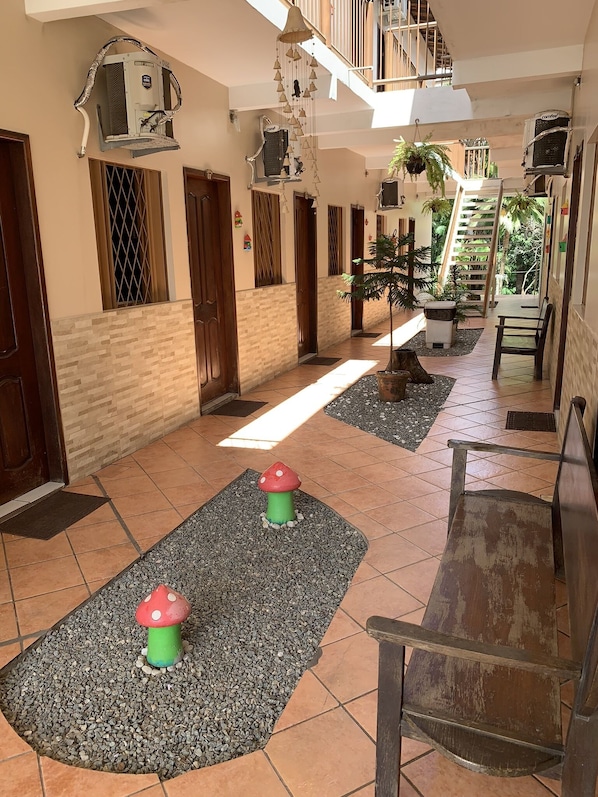 A hallway with tiled flooring, a central bench, and two mushroom-shaped planters.