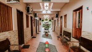Pasillo de hotel con bancos de madera, suelo de baldosas y un elemento decorativo central.