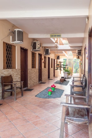 A corridor with tiled flooring, wooden benches, and air conditioning units.