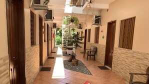 Un pasillo con piso de baldosas, puertas de madera y plantas en macetas.