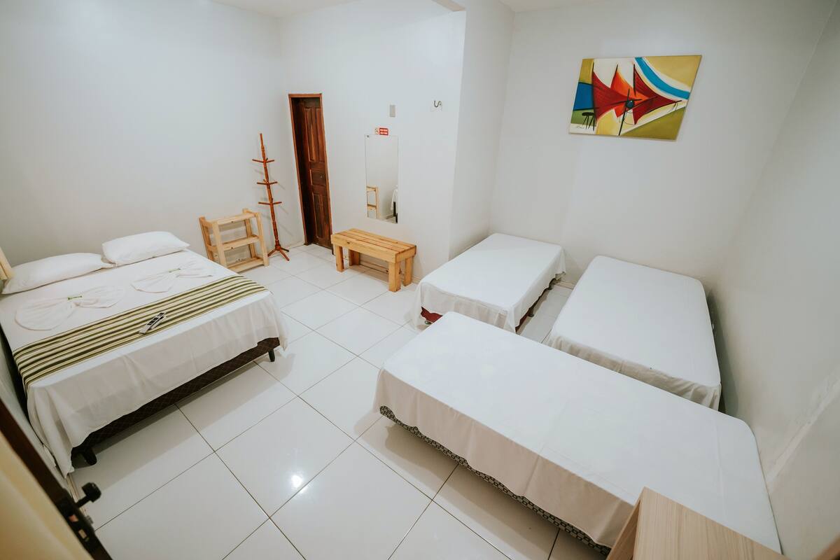 Habitación de hotel con dos camas, un banco de madera, un espejo y un cuadro de colores en la pared.