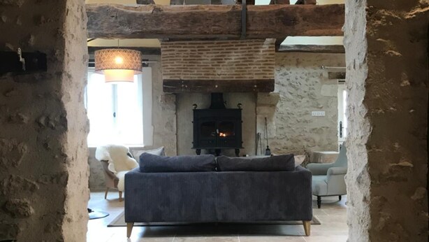 A cozy living room with a stone fireplace, a sofa, and a hanging light fixture. - Colivault (Cande-sur-Beuvron)