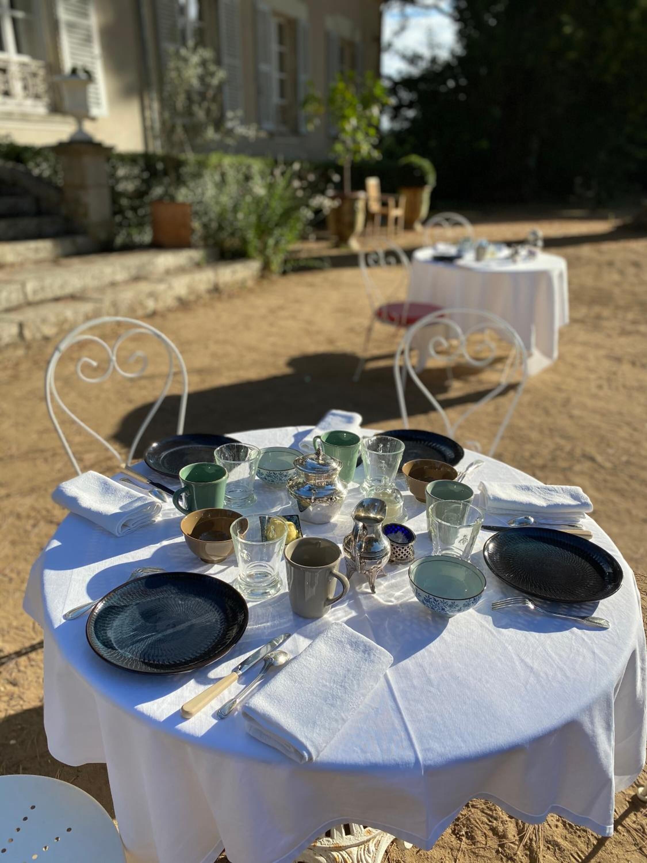A round table set outdoors with various dishes, glasses, and cutlery.