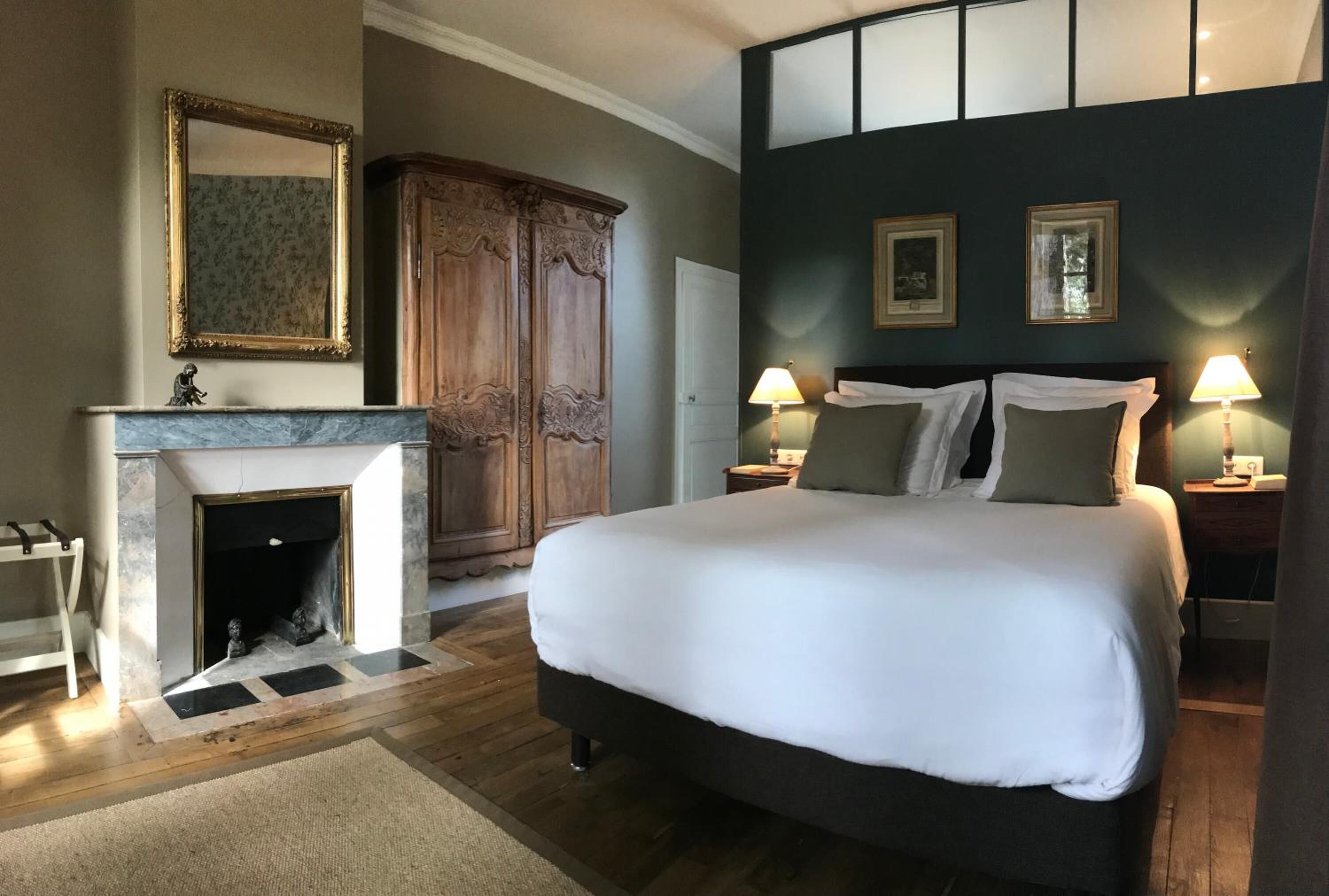Een slaapkamer met een groot bed, een open haard, een kledingkast en twee bedlampen.