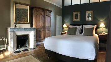 Een slaapkamer met een groot bed, een open haard, een kledingkast en twee bedlampen.