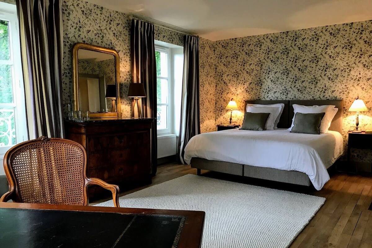 A bedroom with a bed, a dresser, a chair, and a window with curtains.
