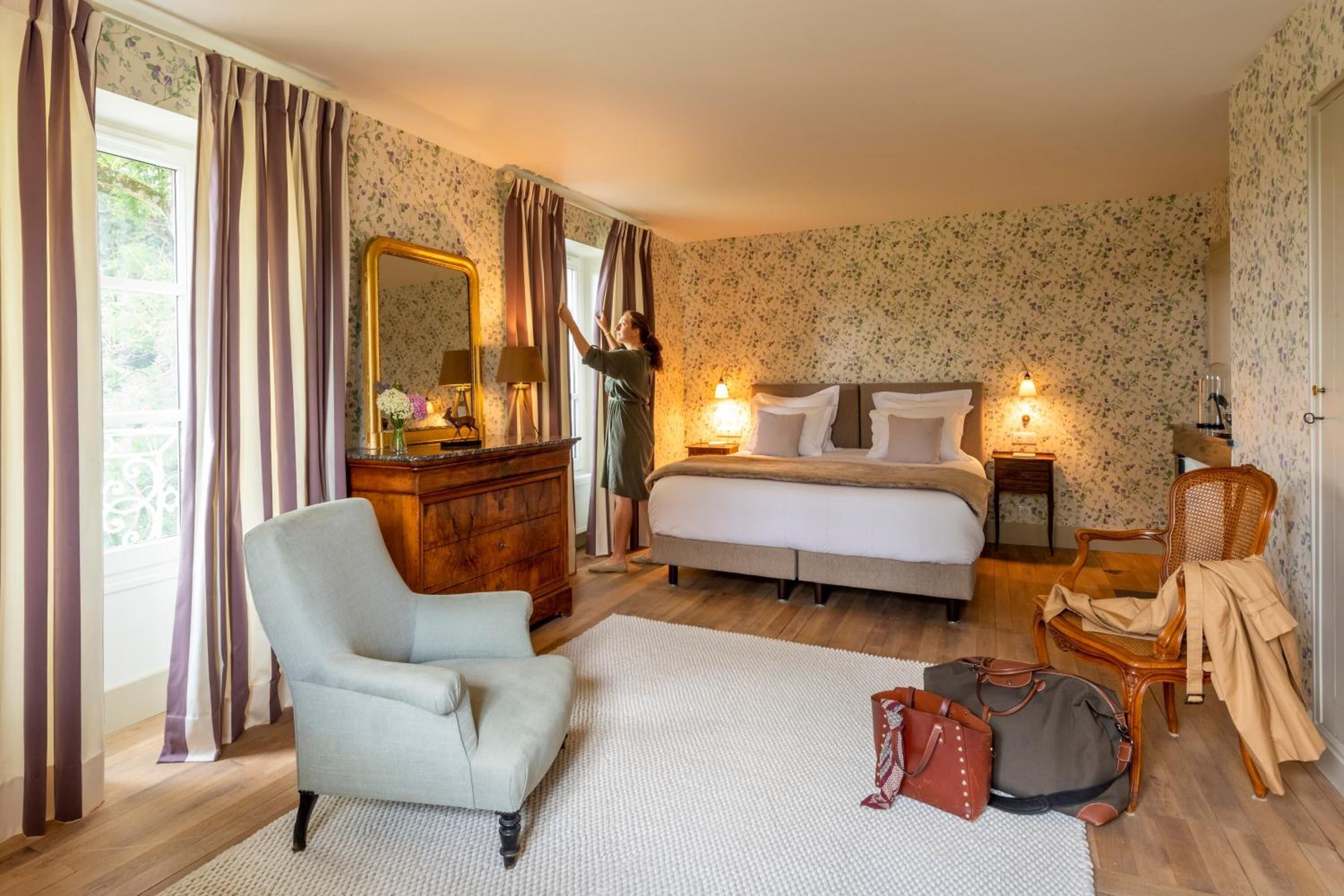 A bedroom with a bed, dresser, chair, and luggage.