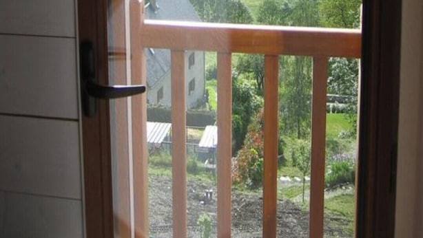 Blick vom Balkon mit Bergeltern, einer grünen Wiese und einem Gebäude in der Ferne.