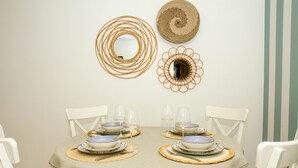 A dining table set for four with white chairs, surrounded by decorative wall mirrors and a striped wall. - Destiny - Caparica apartment (Costa da Caparica)