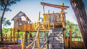 A wooden playground structure with climbing elements and a slide. - Destiny - Caparica apartment (Costa da Caparica)