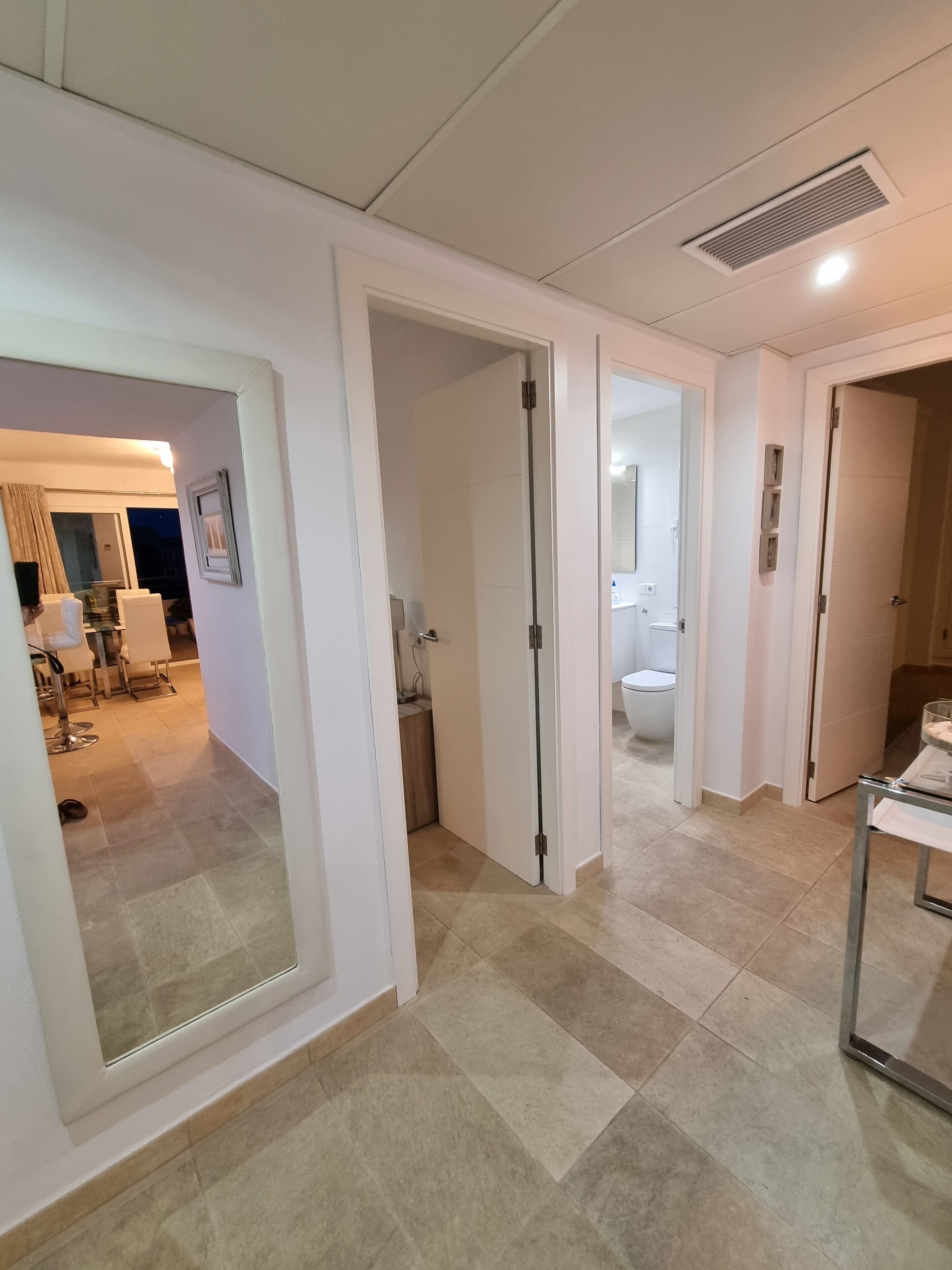 Un couloir d’hôtel avec de nombreuses portes donnant accès à différentes pièces, notamment une salle de bain et un coin repas.