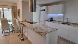 Una cocina moderna con una isla central, armarios blancos y una campana extractora de acero inoxidable.