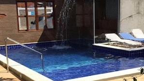 A swimming pool with a waterfall feature, a lounge area with sun loungers, and a view of the surrounding area. - Pousada Francês Praia (Marechal Deodoro)