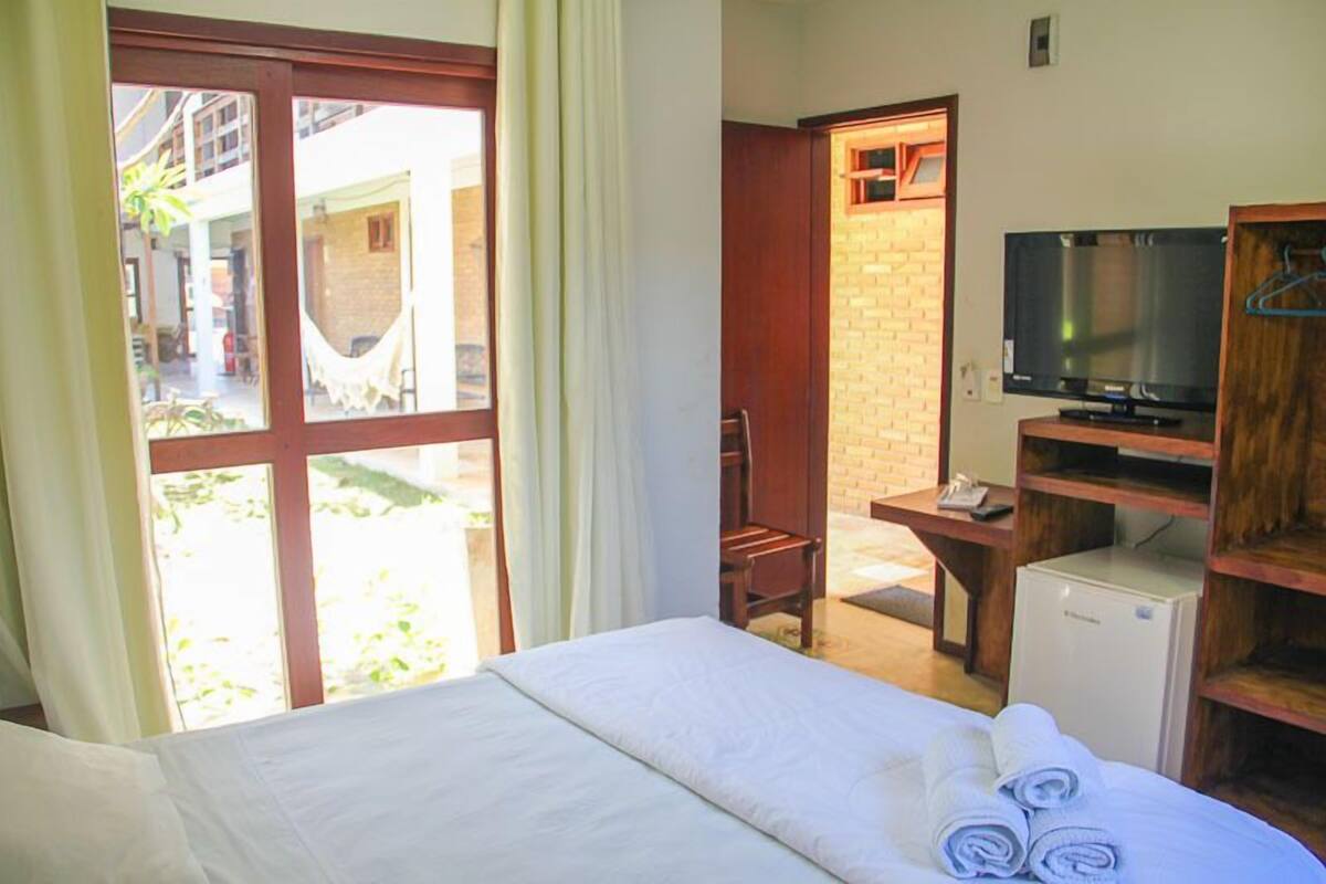 Ein Hotelzimmer mit Bett, Fernseher, Schreibtisch und kleinem Kühlschrank.