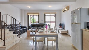 A modern kitchen with a dining area, a sofa, and a staircase. - Kyklades Angie Resort (Paralimni)