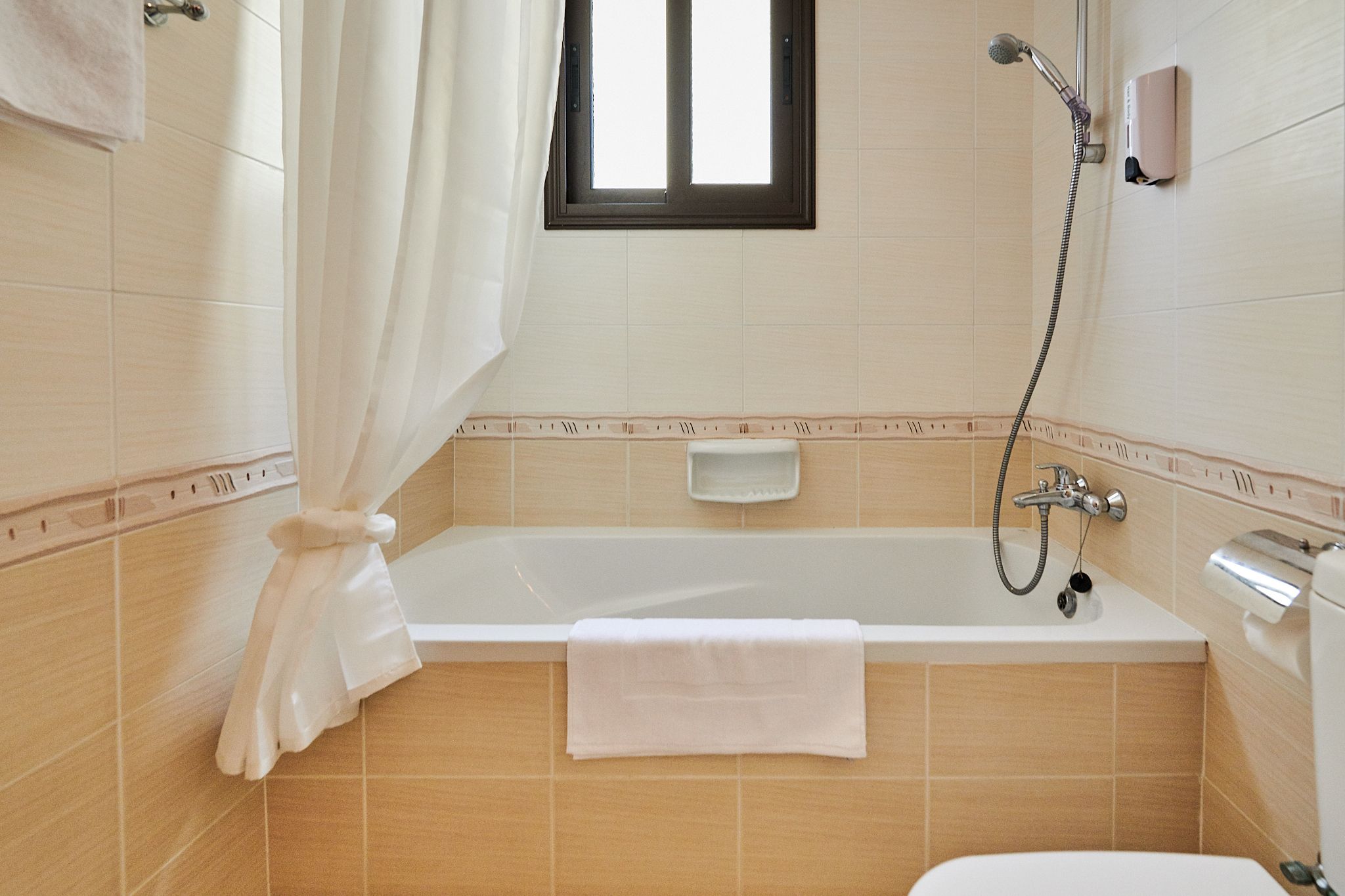 Un bagno con vasca, doccia, una finestra e un portascopevoli.