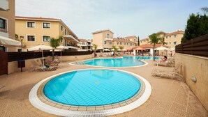 A swimming pool area with multiple pools, sun loungers, and umbrellas. - Kyklades Angie Resort (Paralimni)
