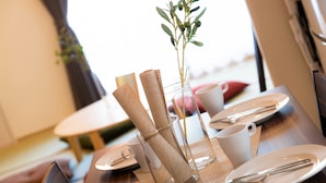 A dining table set with plates, cutlery, and a vase with a plant. - Ateliertokyo 5F (Tokyo)