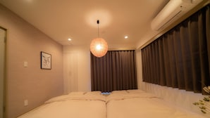 A bedroom with a large bed, a hanging light fixture, and a window with curtains. - Ateliertokyo 5F (Tokyo)