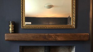 A room with a fireplace, a mirror above it, and a wooden shelf below. - Chefs cottage. Idyllic 18th century cottage. (Kenmore)