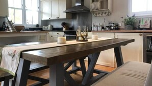 A kitchen with white cabinets, a wooden table, and a black range hood. - Chefs cottage. Idyllic 18th century cottage. (Kenmore)