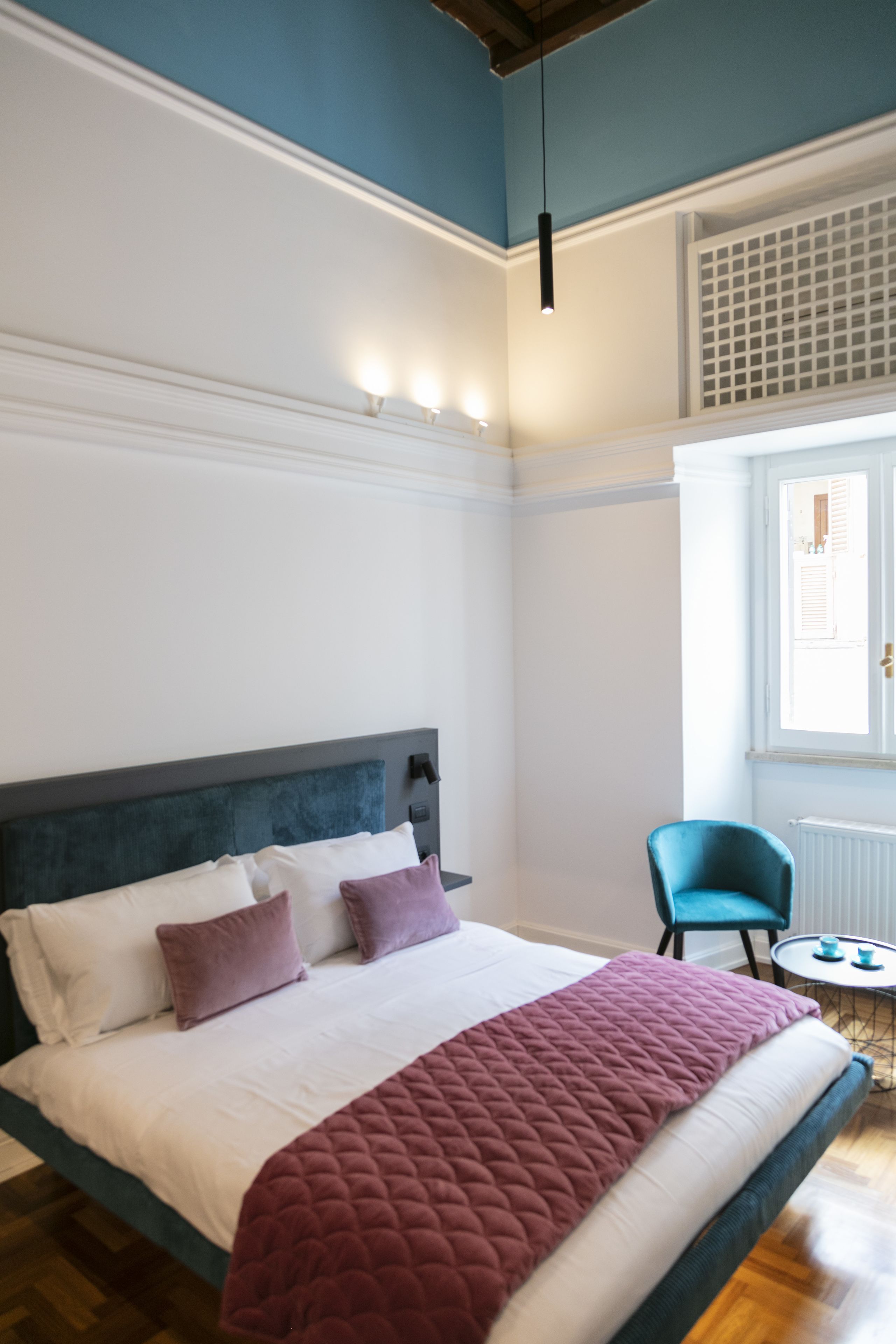 A bedroom with a bed, a chair, and a window.