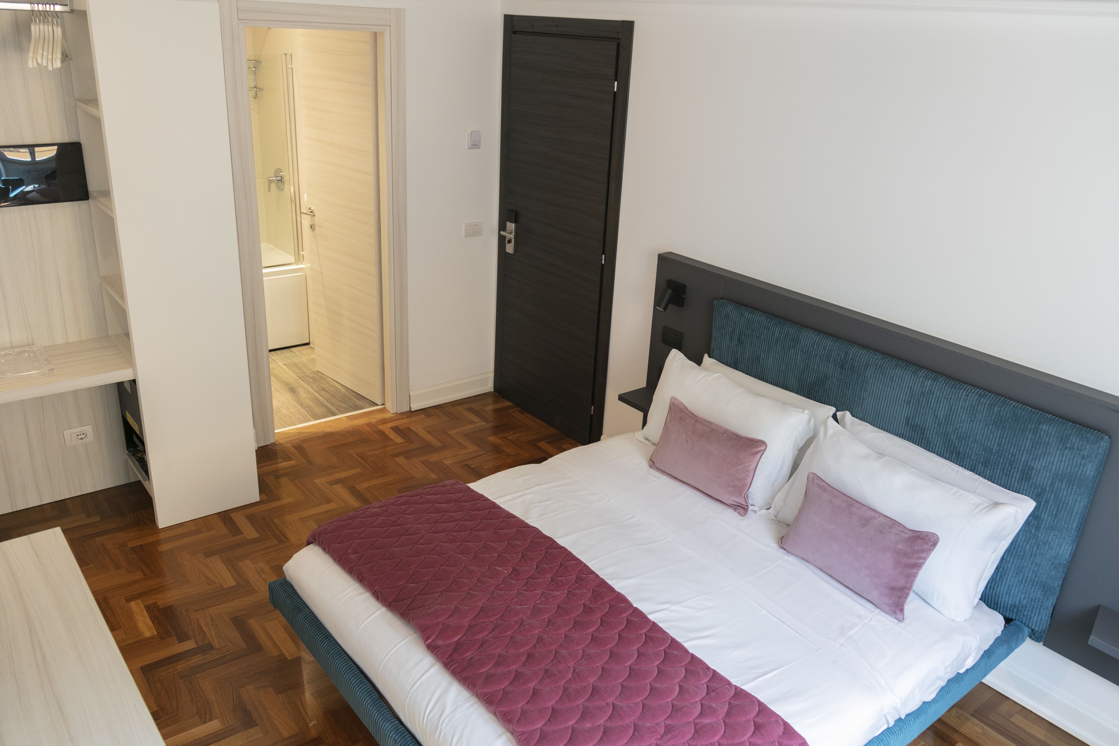 A bedroom with a bed, a wardrobe, and a bathroom door.
