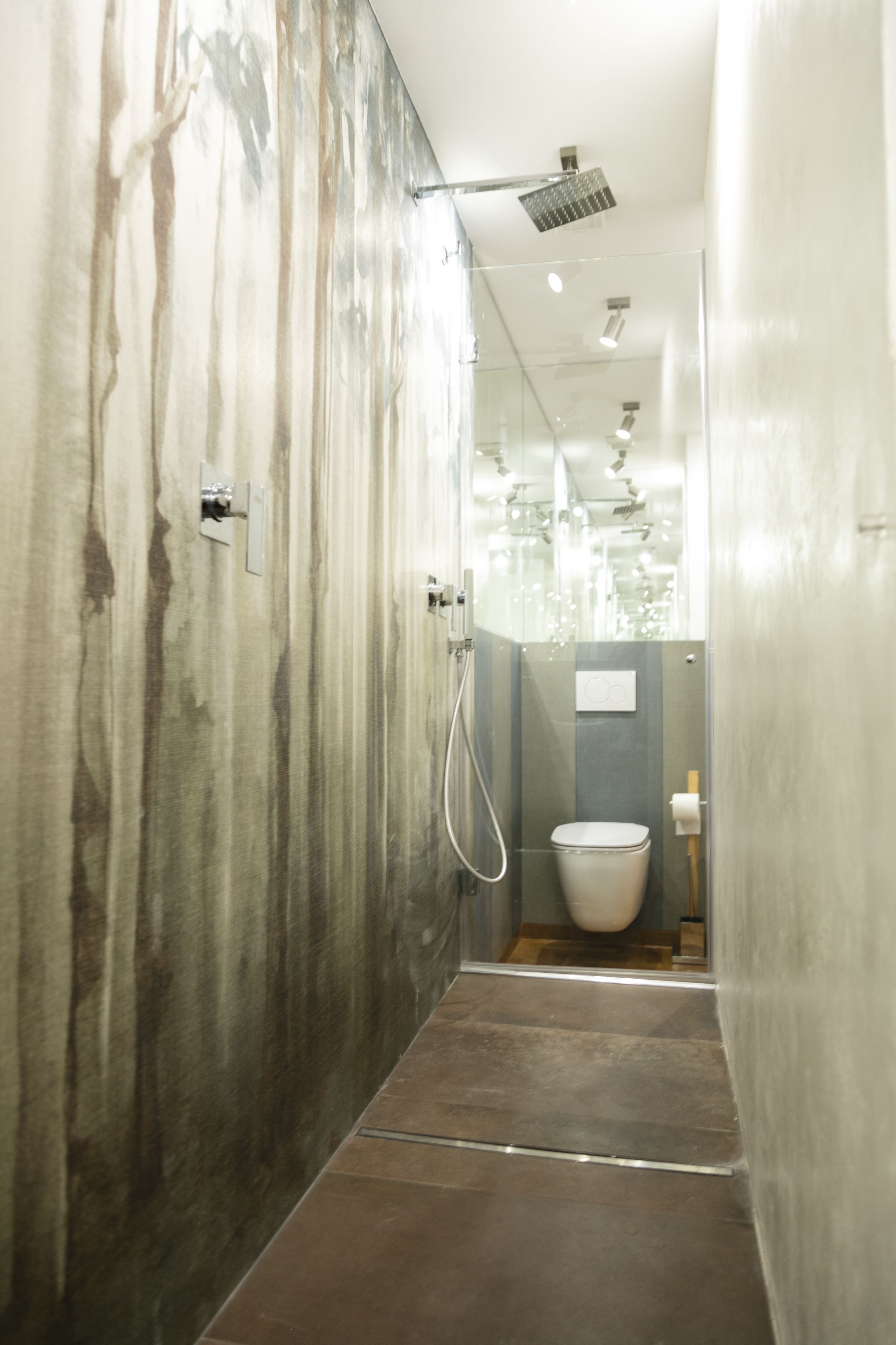 A modern bathroom with a glass partition, a showerhead, and a toilet.