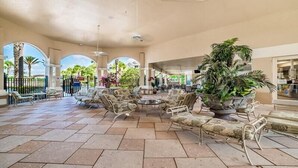 A spacious lobby with a central seating area, surrounded by columns and potted plants. - EV_76604 - 3 Bed 2 Bath Condo with Access to Resort Amenities (Kissimmee)