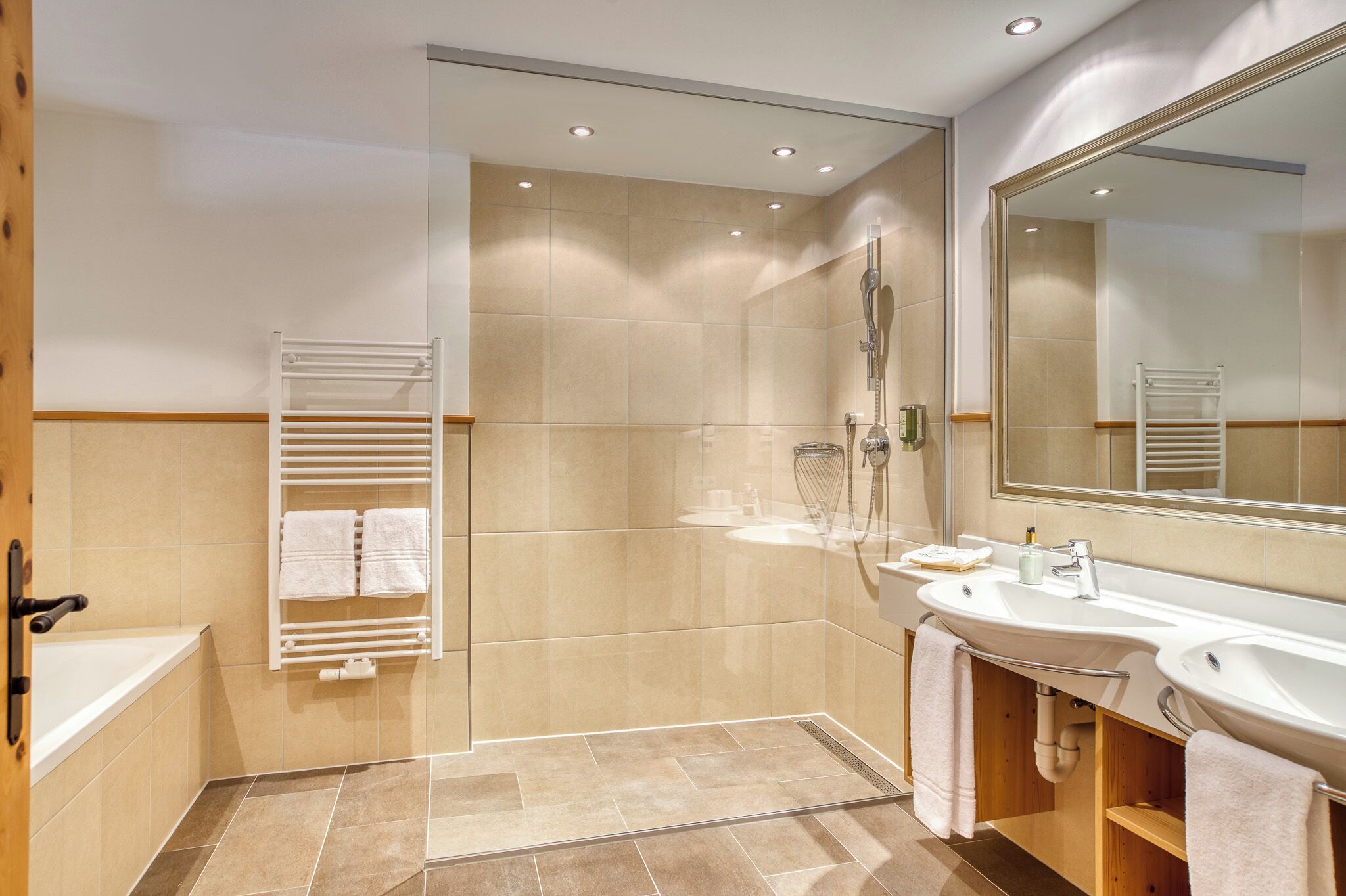A modern bathroom with a bathtub, a walk-in shower, and two sinks.