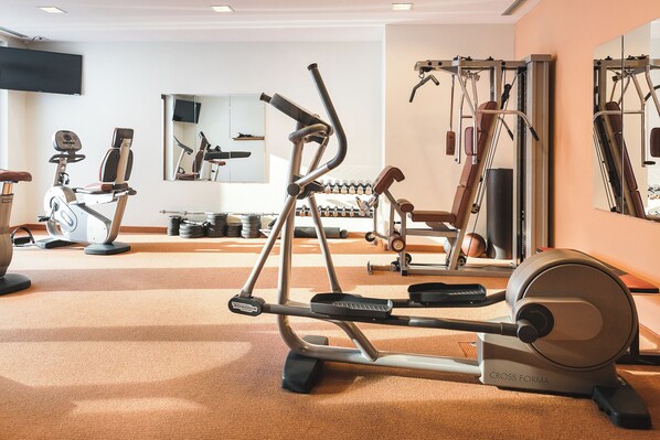 Une salle de sport équipée de divers appareils d’exercice, notamment des tapis de course, des vélos d’appartement et des appareils de musculation.