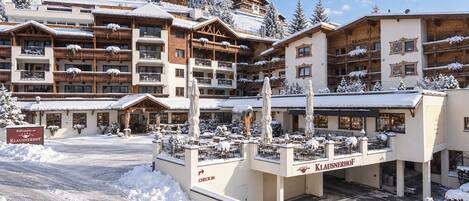 A snow-covered hotel with multiple balconies and a check-in area.