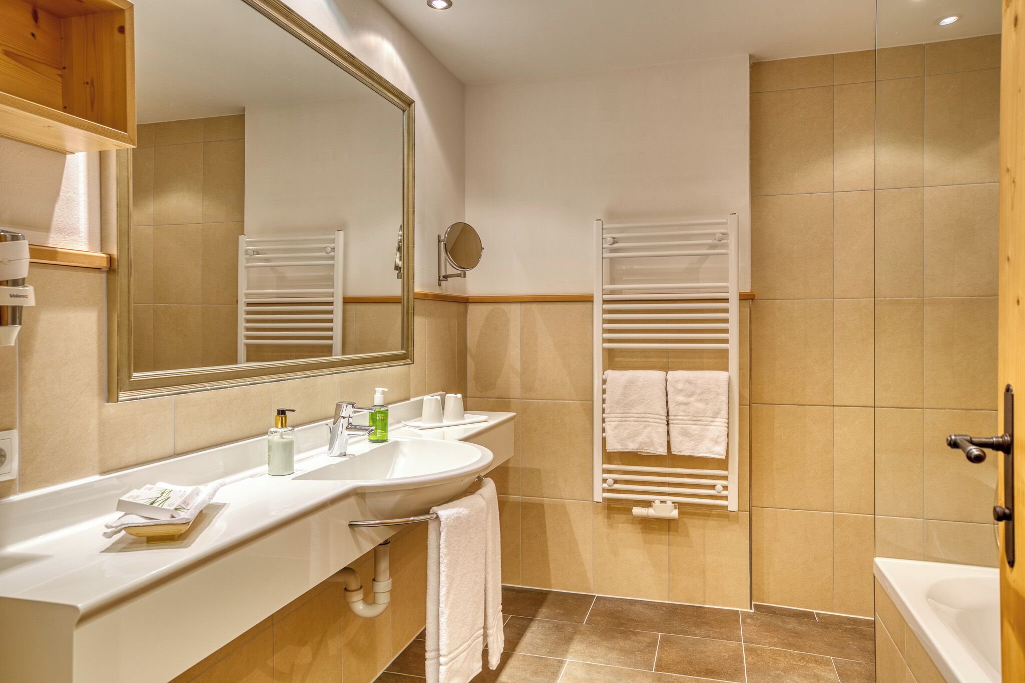 Un baño moderno con dos lavabos, un espejo, un perchero para toallas y una zona de ducha.