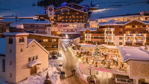 A snow-covered town with a central building featuring a large staircase and a sign reading "Check In". - Hotel Klausnerhof (Tux)