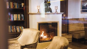 A cozy living room with a fireplace, a bookshelf, and comfortable seating. - Hotel Klausnerhof (Tux)