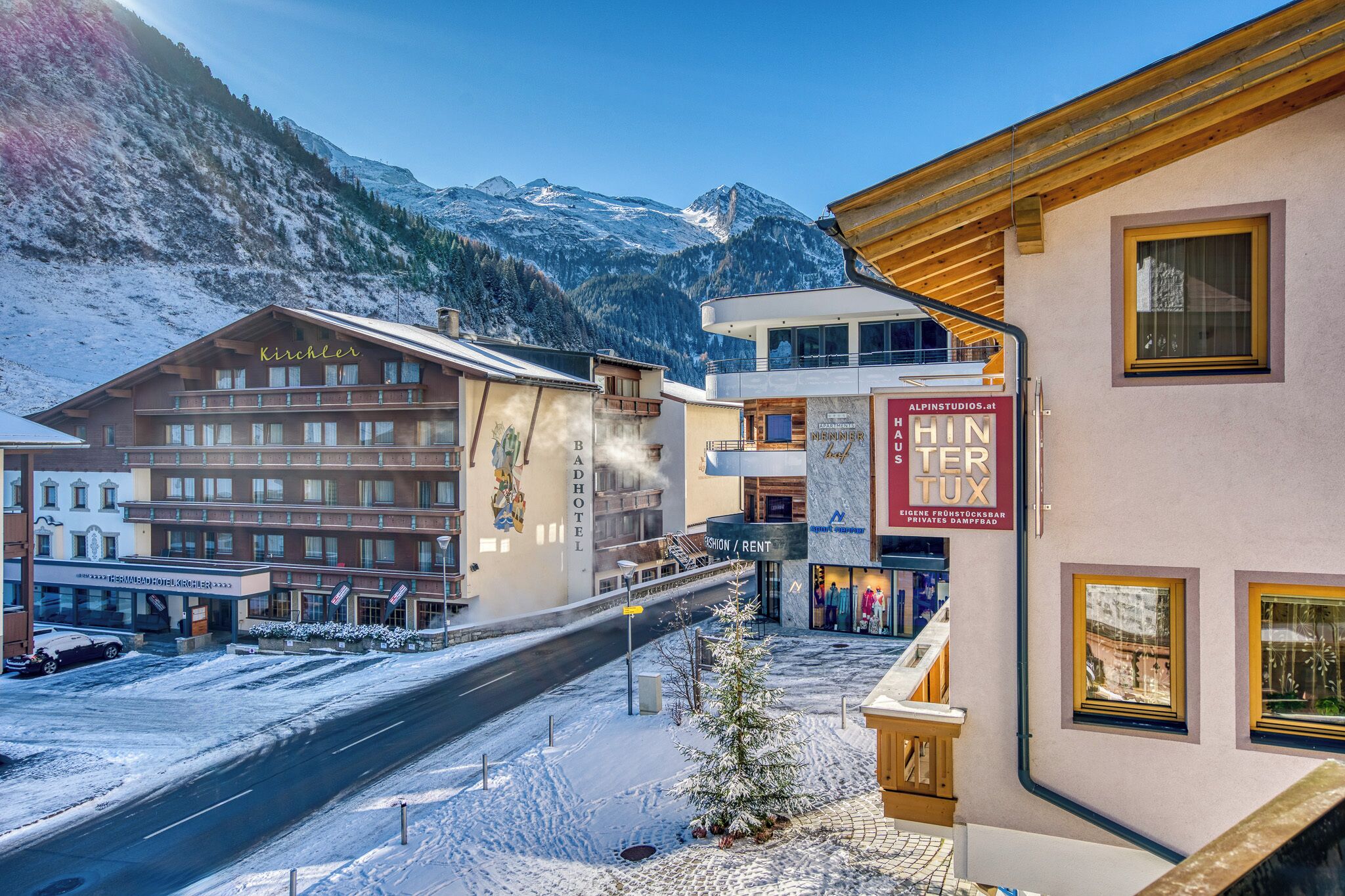 Un hôtel situé au pied d’une montagne, avec un télésiège à proximité et une enseigne indiquant « Alpin Studios ».