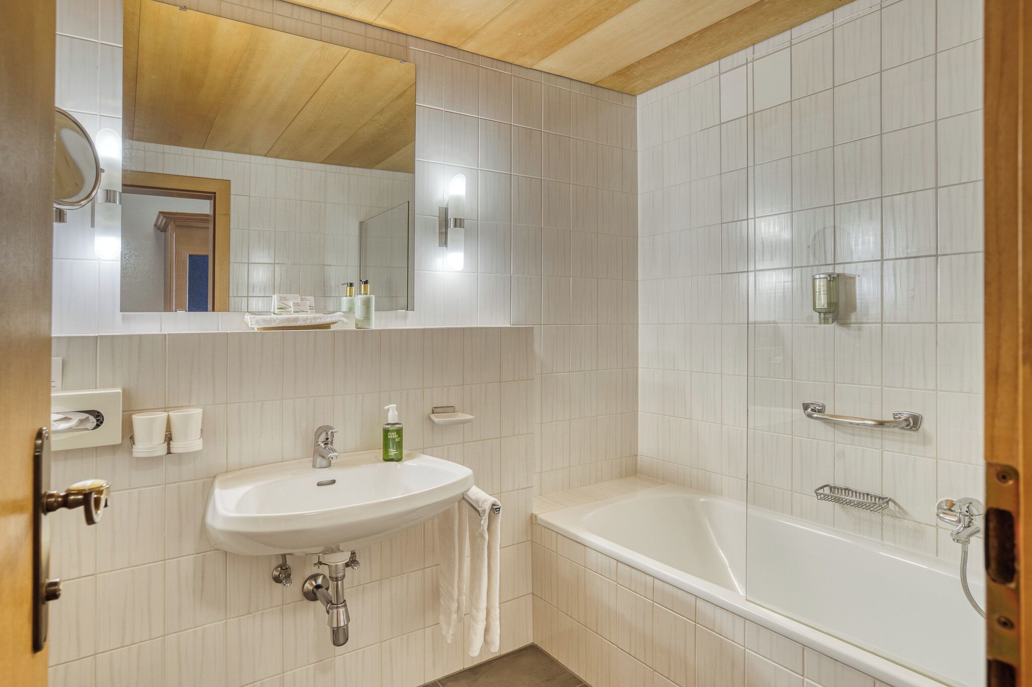 A bathroom with a sink, mirror, and bathtub.