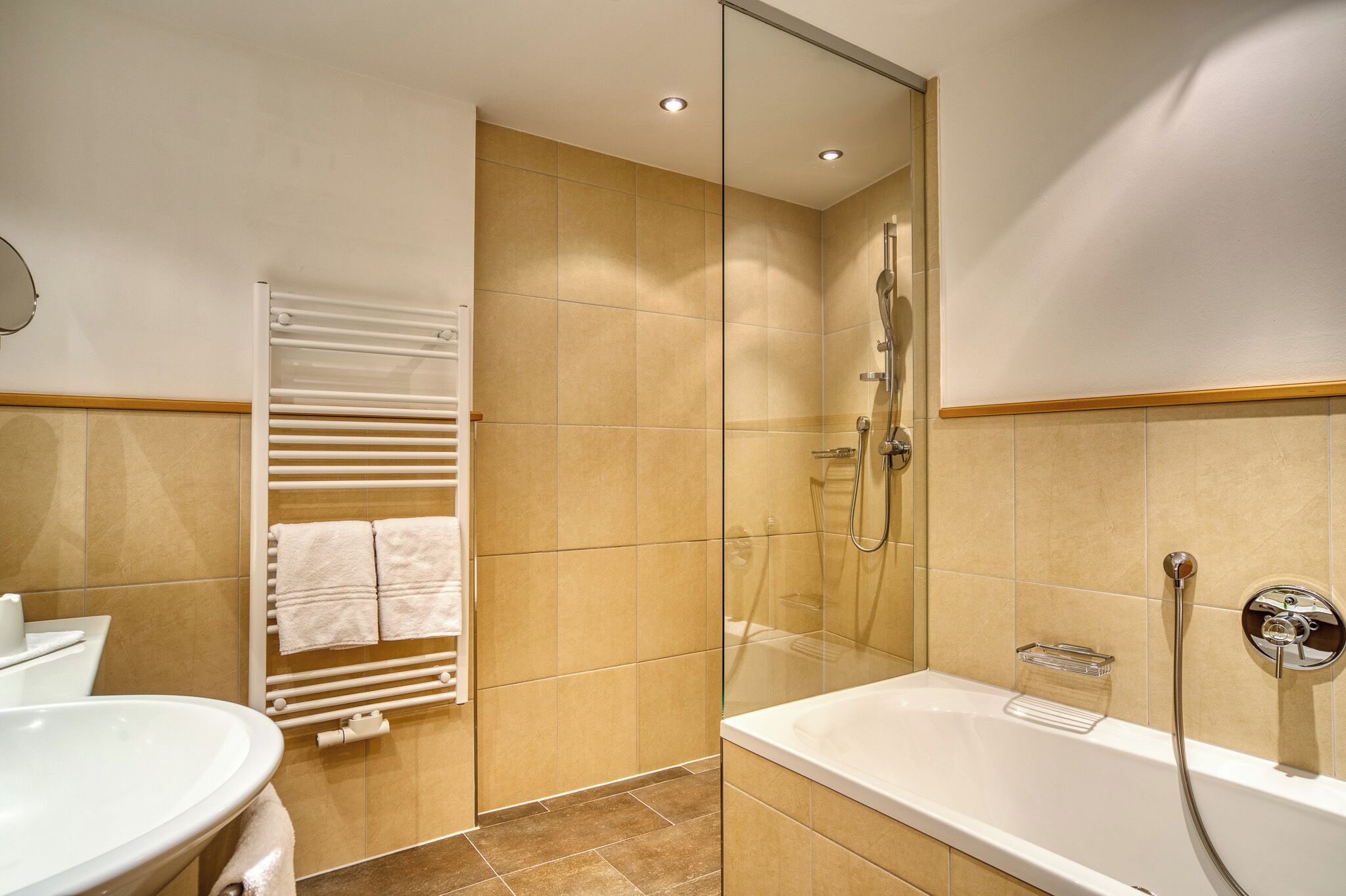 Un bany modern amb dutxa envidriada, una banyera blanca i un lavabo blanc.