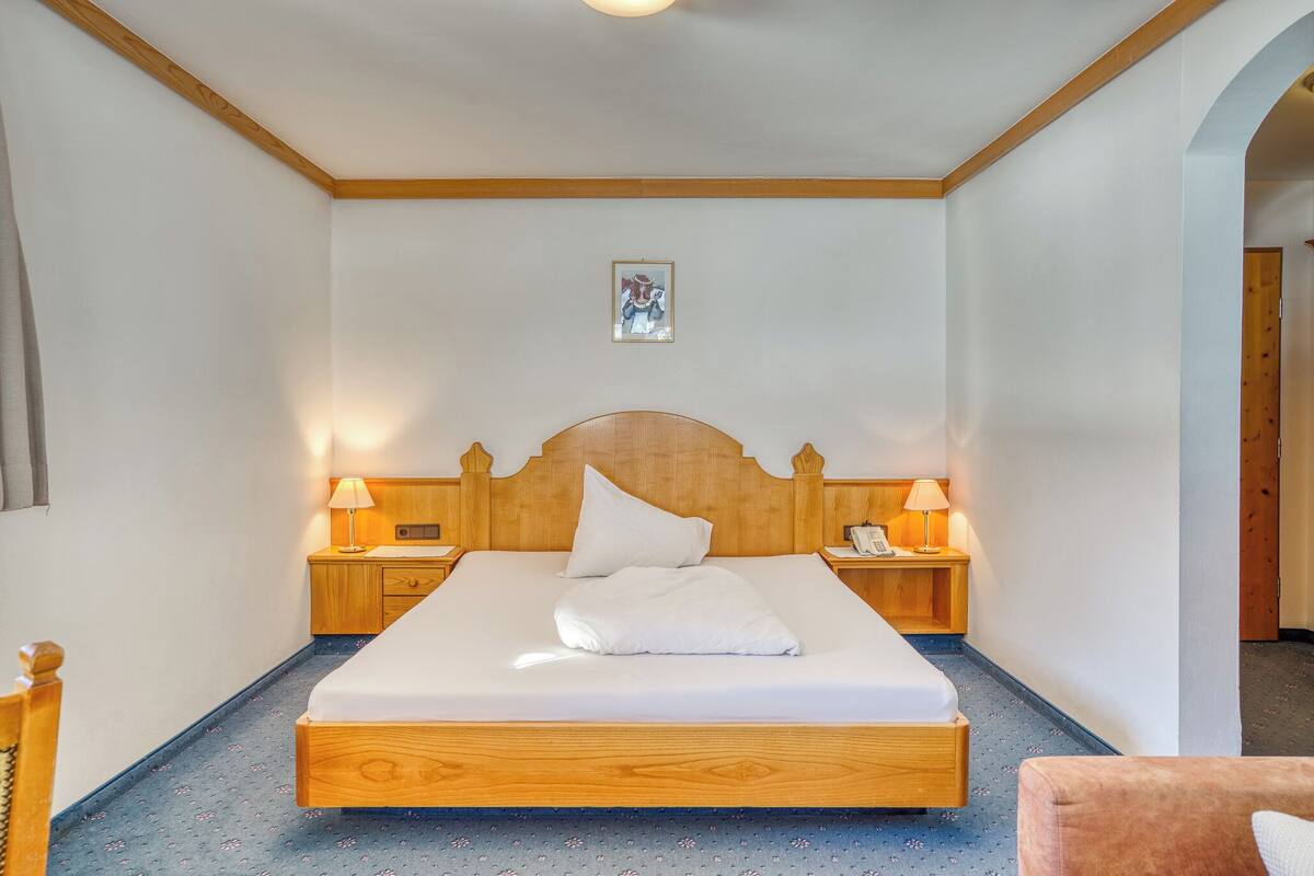 A neatly made bed with a wooden headboard, two bedside tables with lamps, and a small framed picture on the wall.