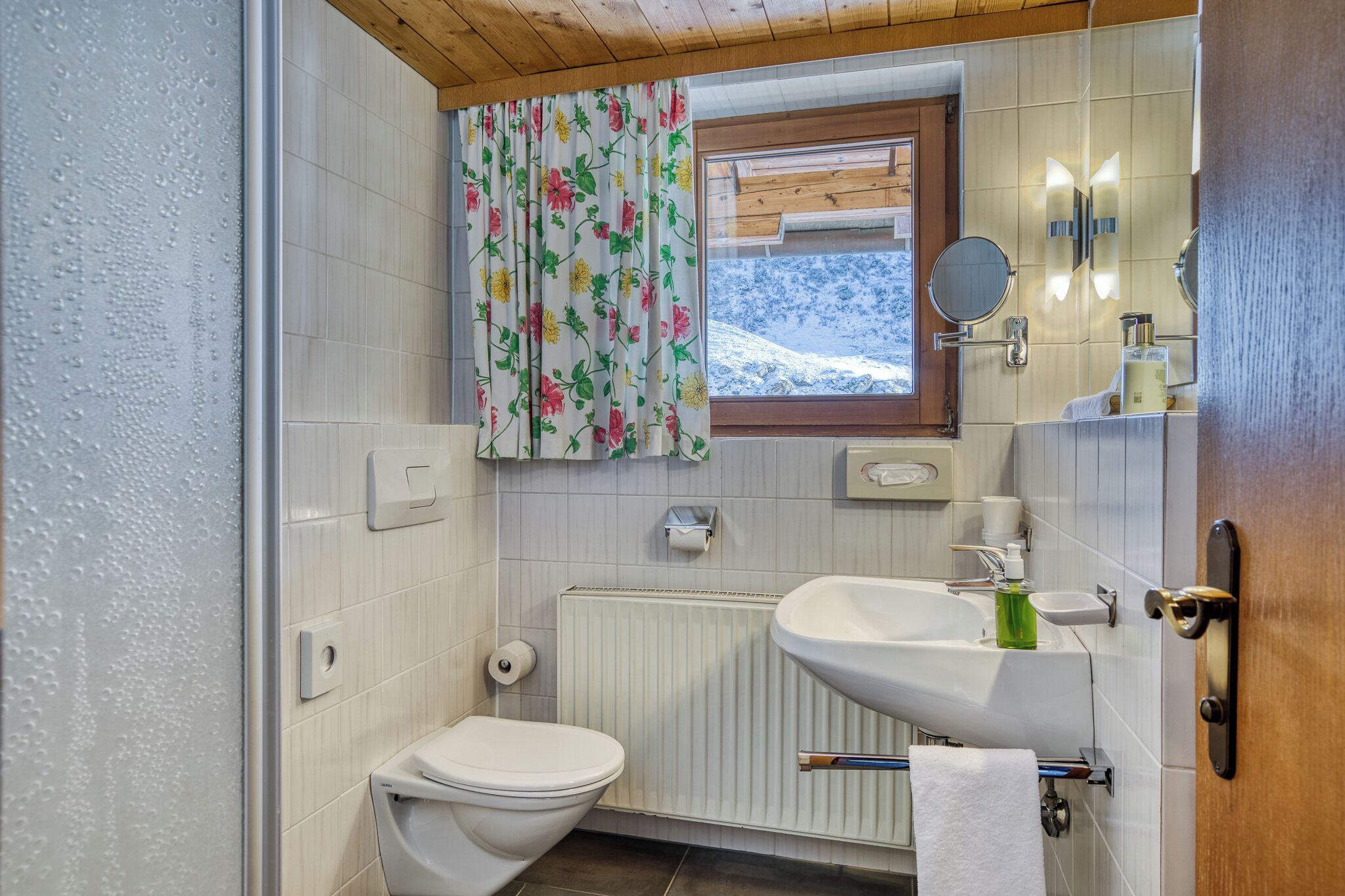Un baño con inodoro, lavabo y ventana con vista a una montaña nevada.