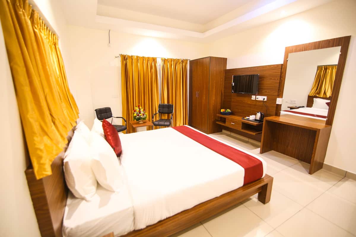 A hotel room with a large bed, wooden wardrobe, desk, and a mirror.