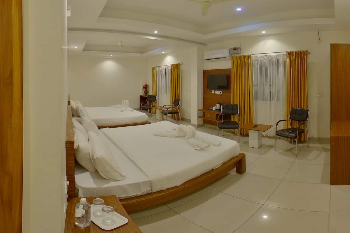 A hotel room with two beds, a desk, a chair, a TV, and a ceiling fan.
