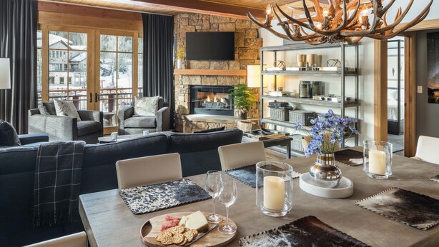 A cozy living room with a fireplace, comfortable seating, and a dining area with a table set for a meal. - Outpost: Crystal Springs 306 - Ski-In/Ski-Out! (Teton Village)